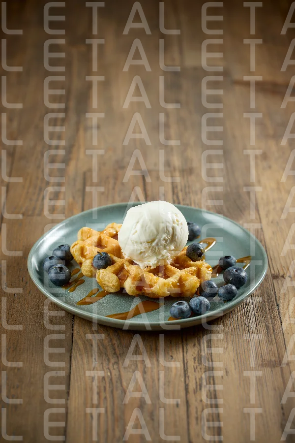 plate of belgian waffle with caramel sauce and blueberries